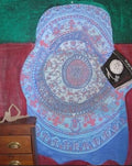 Still life featuring a blue and lavender mandala, red and green background, wooden chest, and tilted book.